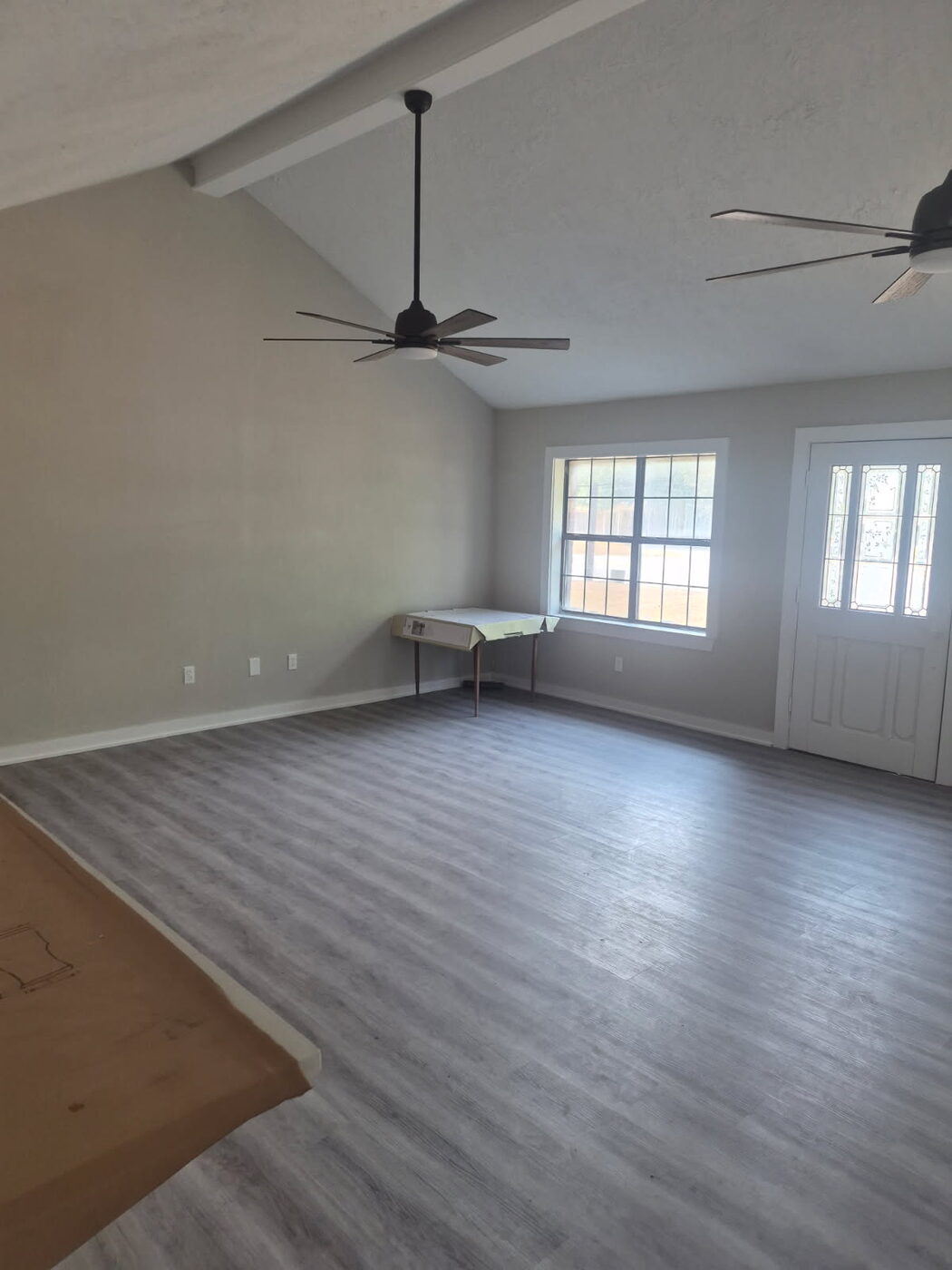 Open living room with new gray plank flooring, fresh paint and ceiling fans