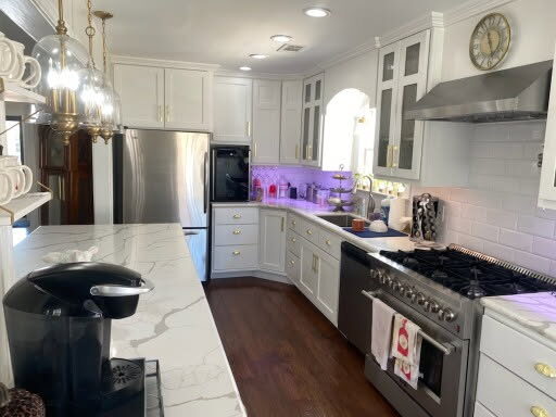 Kitchen with white cabinets, subway tile, stainless range hood and marble-look island