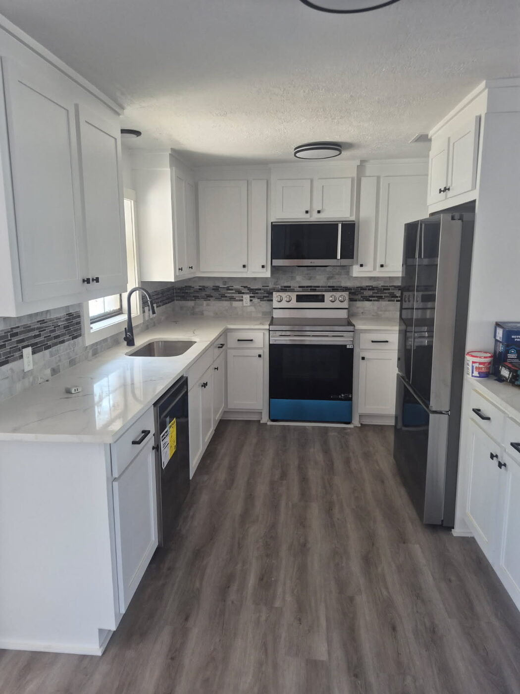 Galley kitchen with white cabinets, quartz counters and gray plank flooring