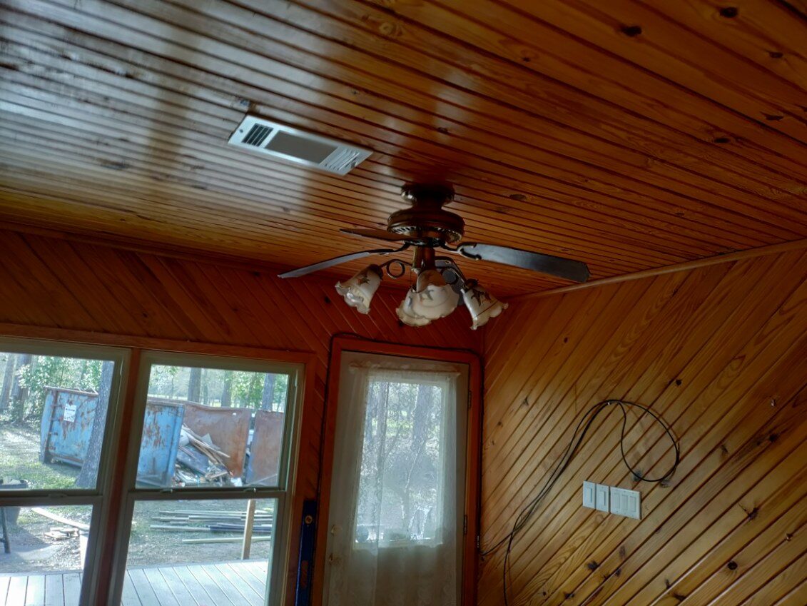 Wood-paneled room with large windows, French door and ceiling fan